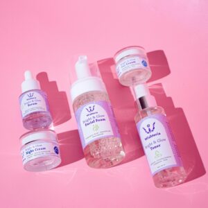 Flat lay of various skincare products on a vibrant pink background.
