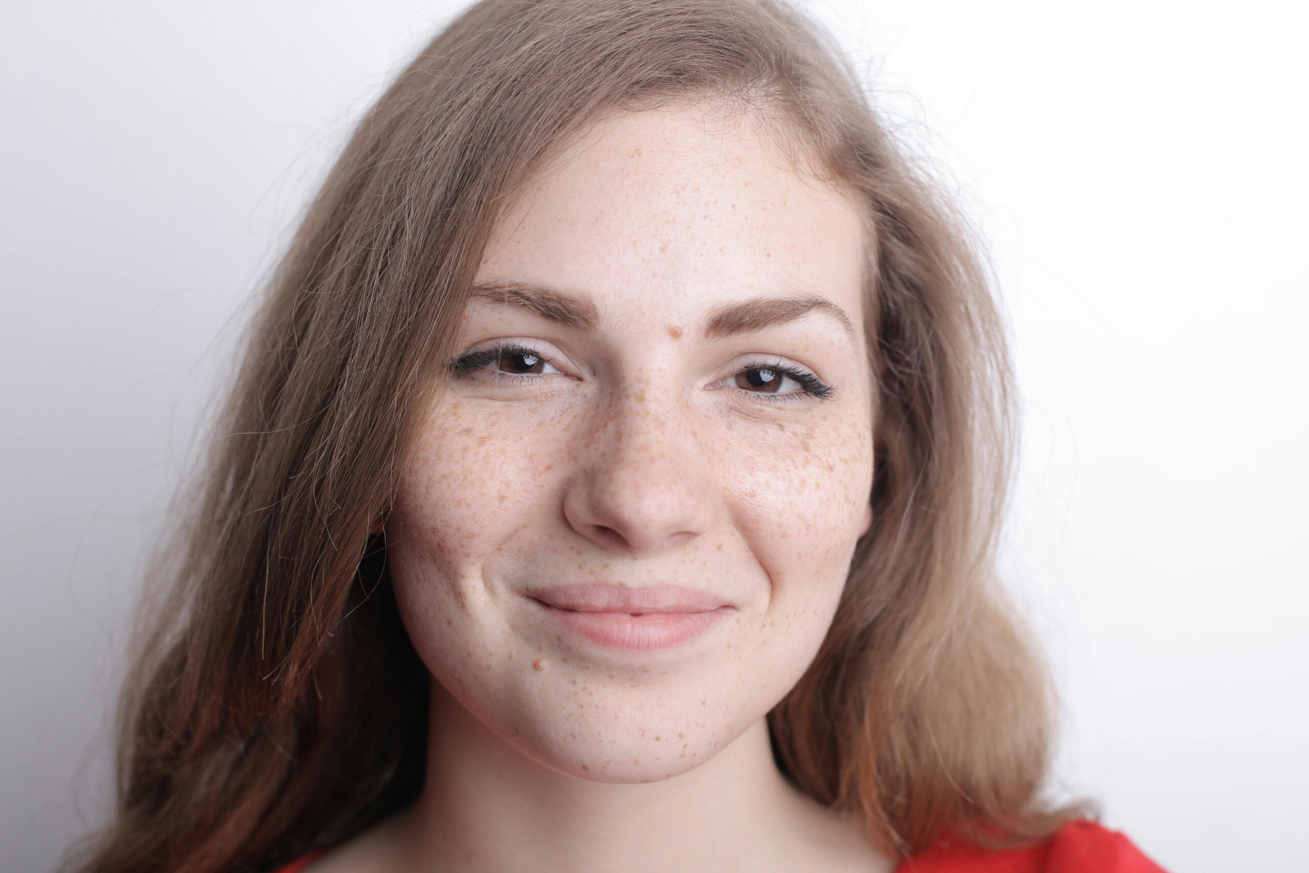 Close-up portrait of a smiling young woman with freckles and natural beauty.
